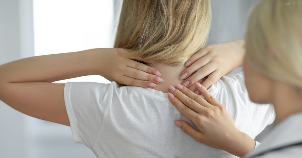 Provider examining the back of a patient's neck during a buffalo hump evaluation (model)