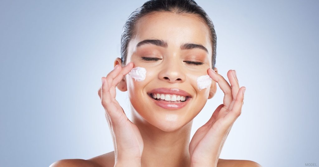 Woman applying sunscreen to her face (model)