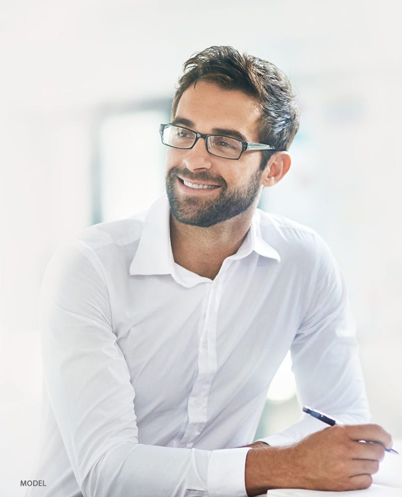 Man with glasses and white button up shirt holding a pen